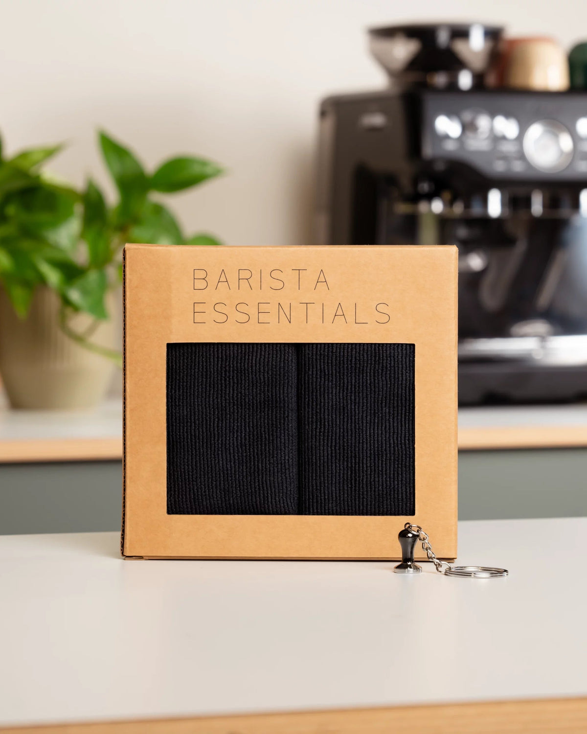 Geschenkset von Barista Essentials für Heim-Baristas mit schwarzen Barista-Tüchern und einem Schlüsselanhänger in Form eines Tamper